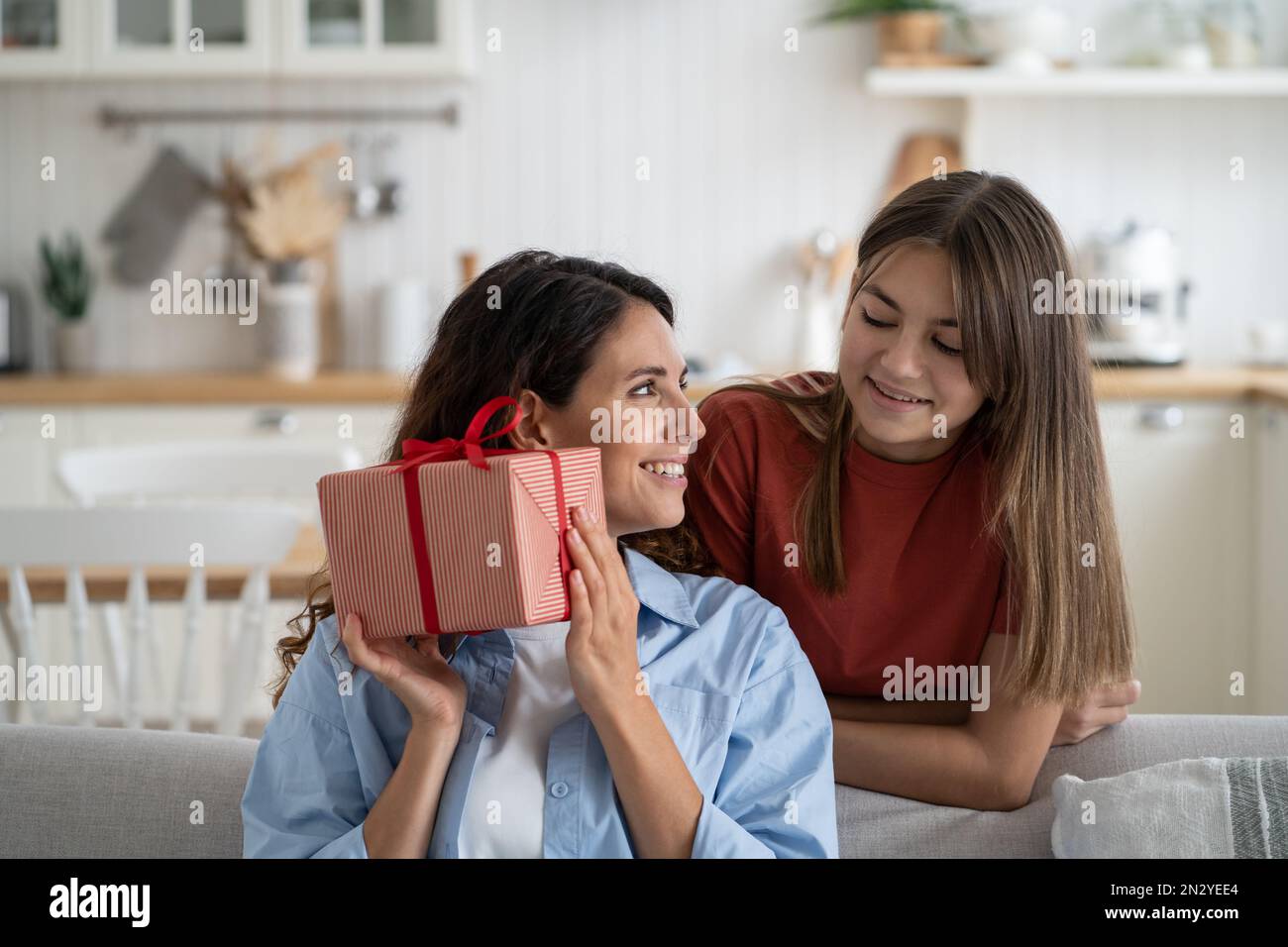 Felice famiglia di festa di donna e ragazza adolescente che dà la scatola regalo della madre in vacanza o il compleanno Foto Stock