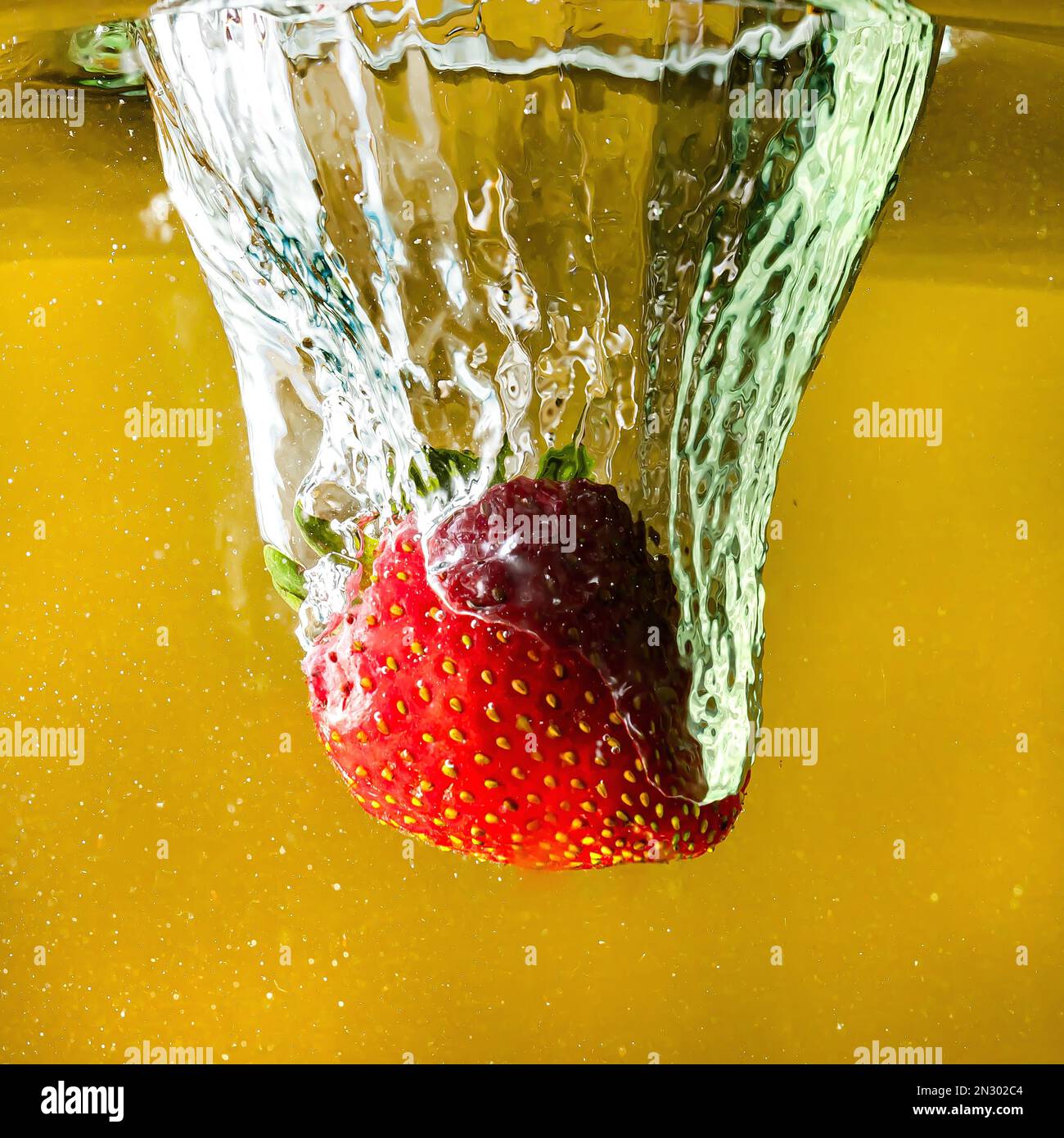 le fragole mature cadono nell'acqua sollevando spruzzi e bolle d'aria Foto Stock