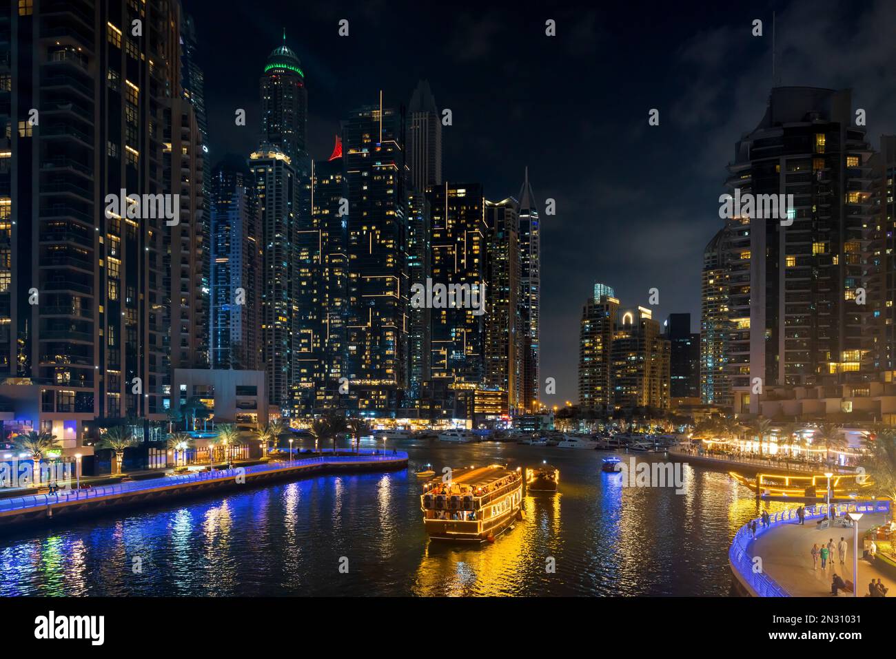 Il paesaggio urbano di Dubai Marina di notte con grattacieli illuminati e barche nel canale. EMIRATI ARABI UNITI Foto Stock