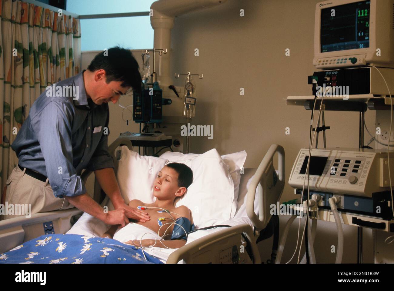 Chirurgo con paziente bambino in reparto di terapia intensiva ospedaliera. Foto Stock