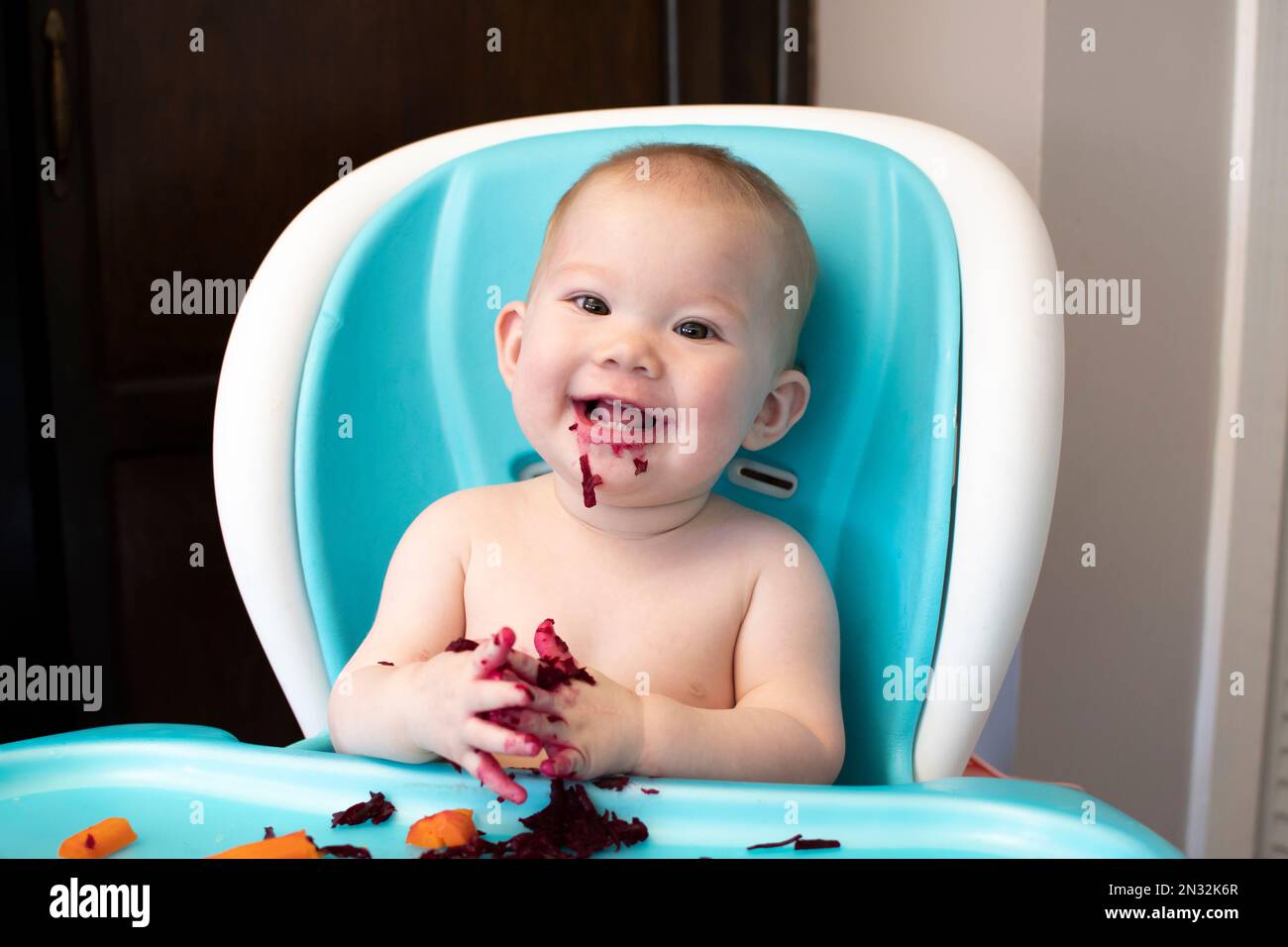 Il bambino che mangia gli alimenti solidi in un seggiolone. Svezzamento guidato dal bambino. Il bambino mangia sano Foto Stock
