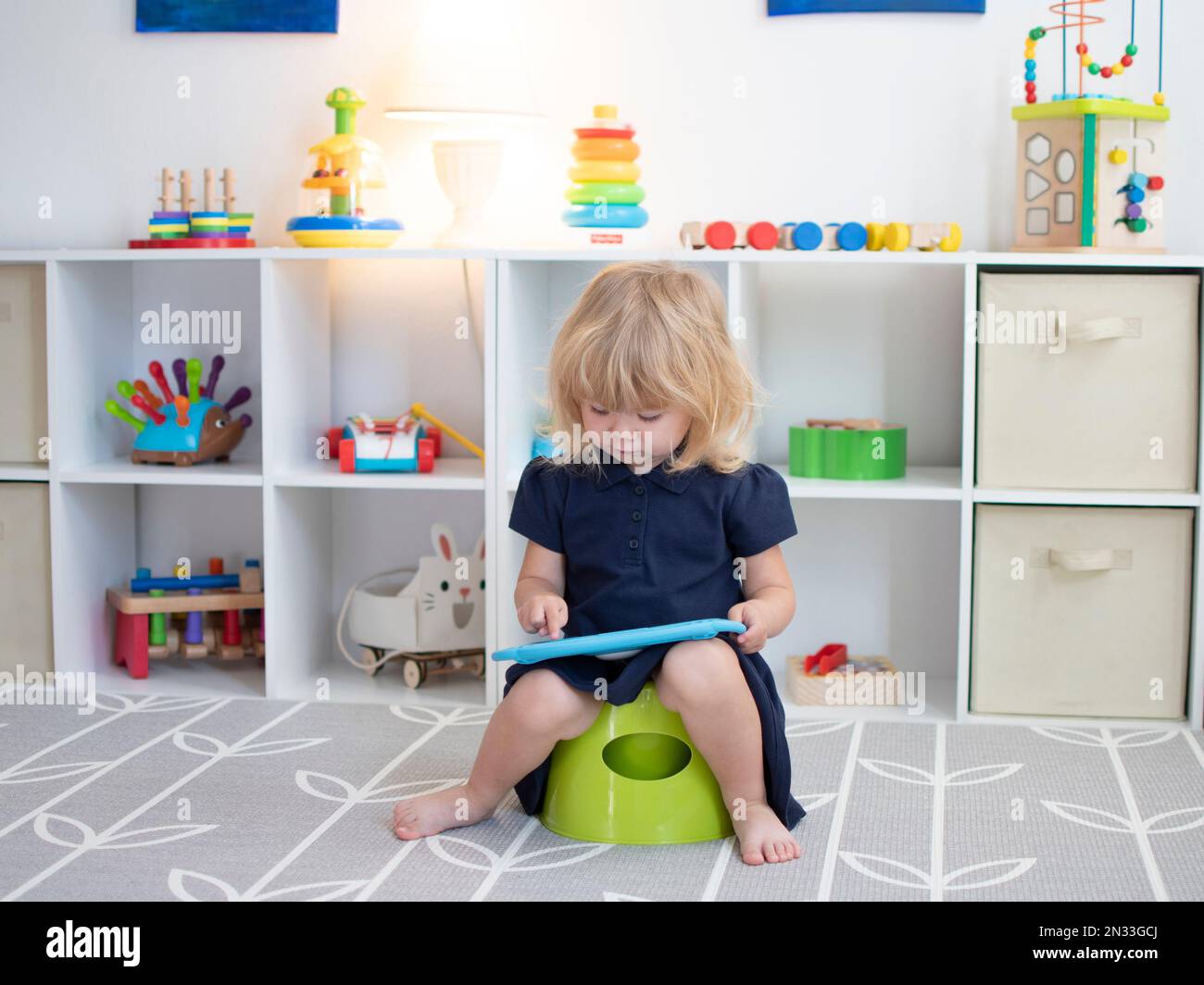 Bambino caucasico seduto su un vasino con la compressa Foto Stock