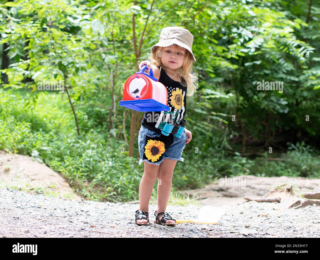 Bambina caucasica in esplorazione all'aperto. Elenco dei secchielli estivi per bambini Foto Stock