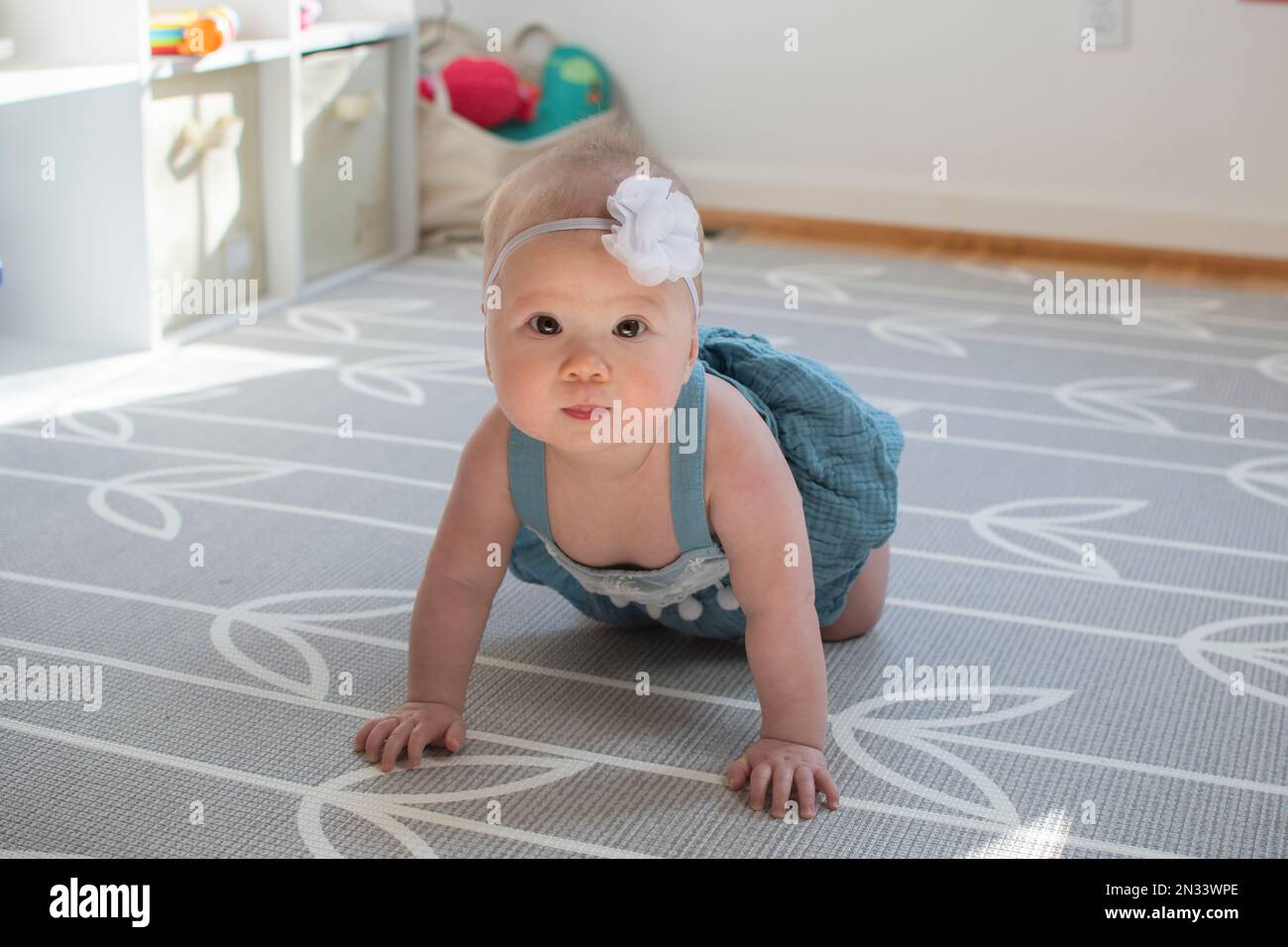 Cute piccola ragazza caucasica bambino imparando come strisciare Foto Stock
