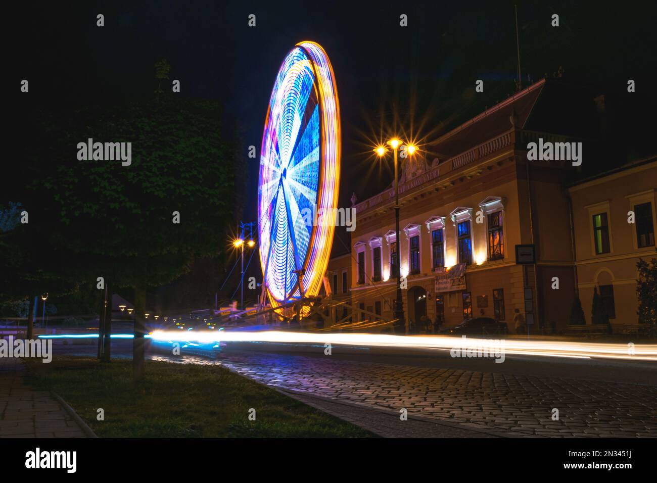 Lunga esposizione ripresa di una ruota panoramica in movimento illuminata di notte, Balassagyarmat, Ungheria Foto Stock