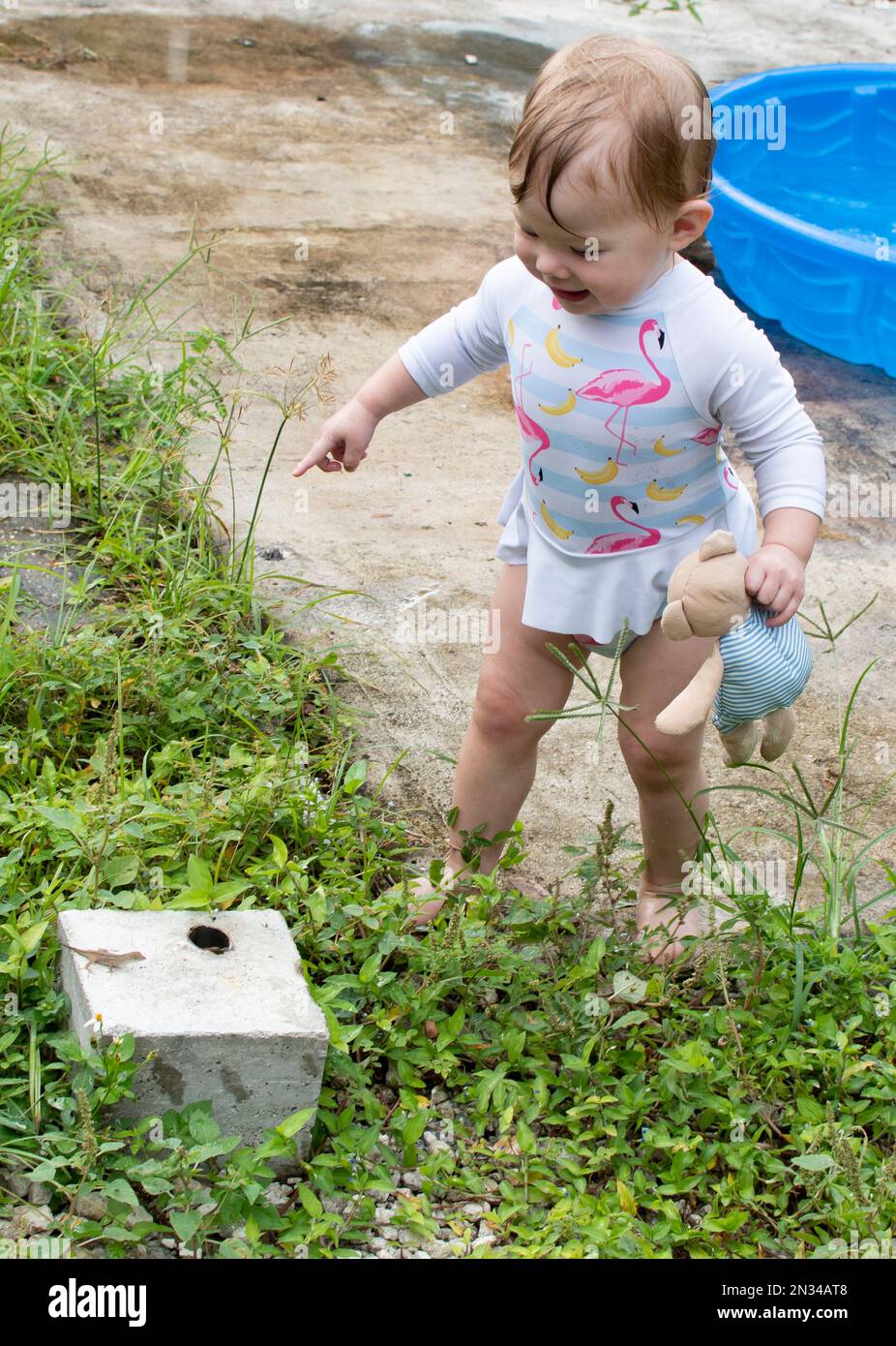 La bambina caucasica ha trovato una lucertola nel cortile. Esplorare bambino Foto Stock