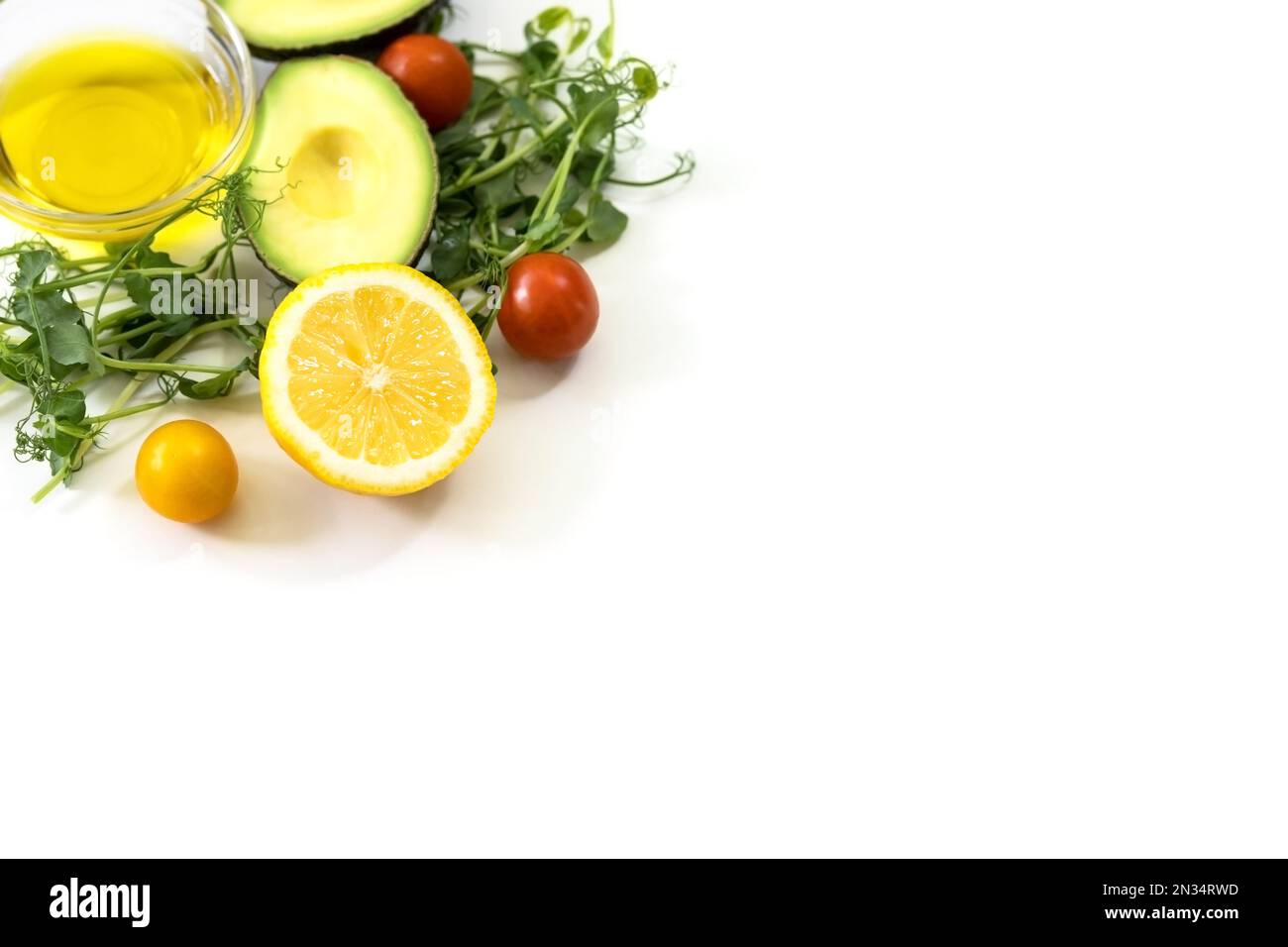 Ingredienti di cibo sano. Germogli di micro piselli verdi, olio d'oliva, cetriolo, pomodoro, avocado, limone. Ketogenic basso concetto di dieta dei carbs. Foto Stock
