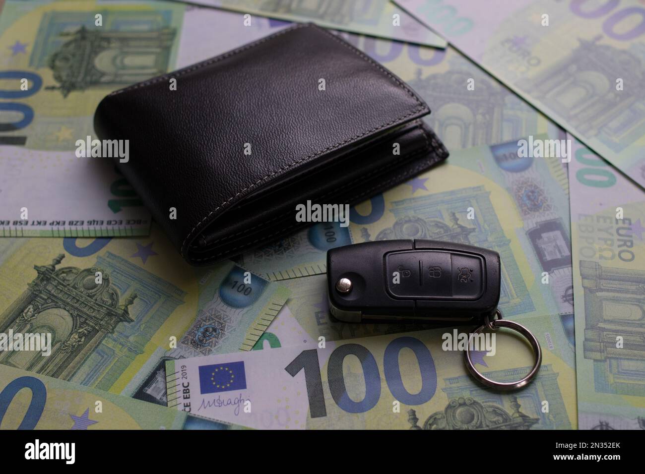 il portafoglio nero e la chiave dell'auto sono su banconote da 100 euro Foto Stock