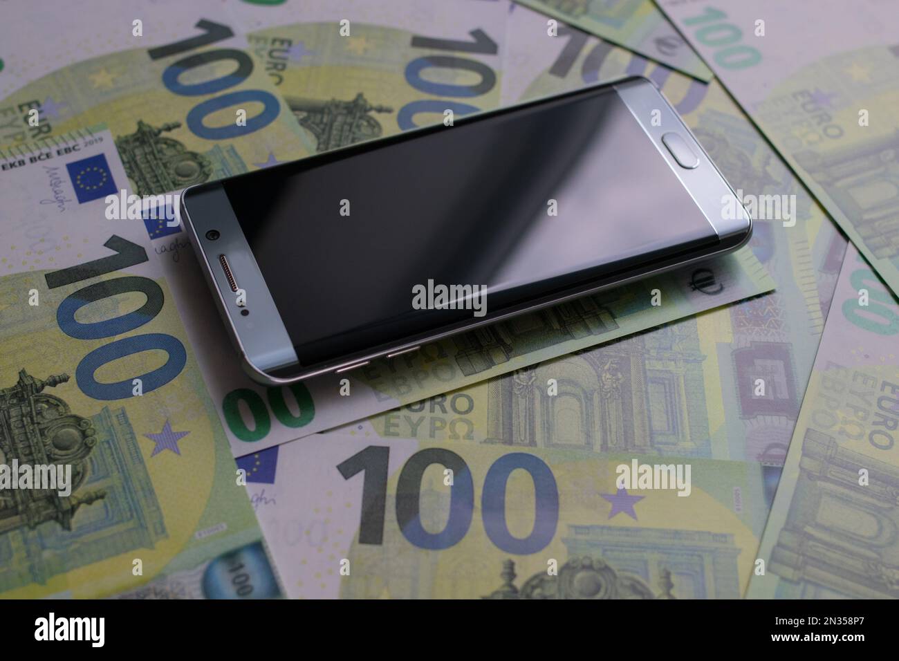 smartphone si trova su 100 banconote in euro Foto Stock