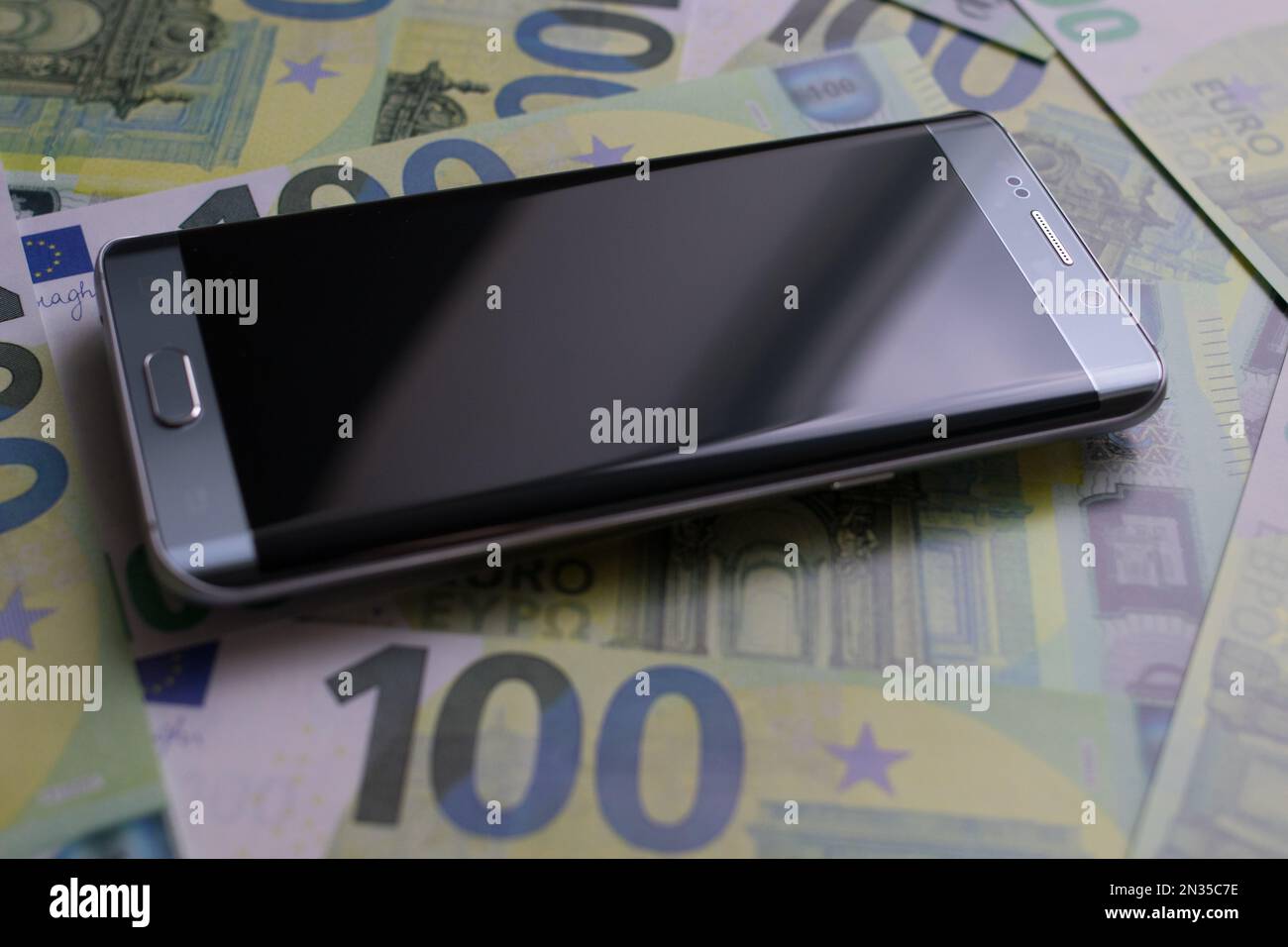 smartphone si trova su 100 banconote in euro Foto Stock
