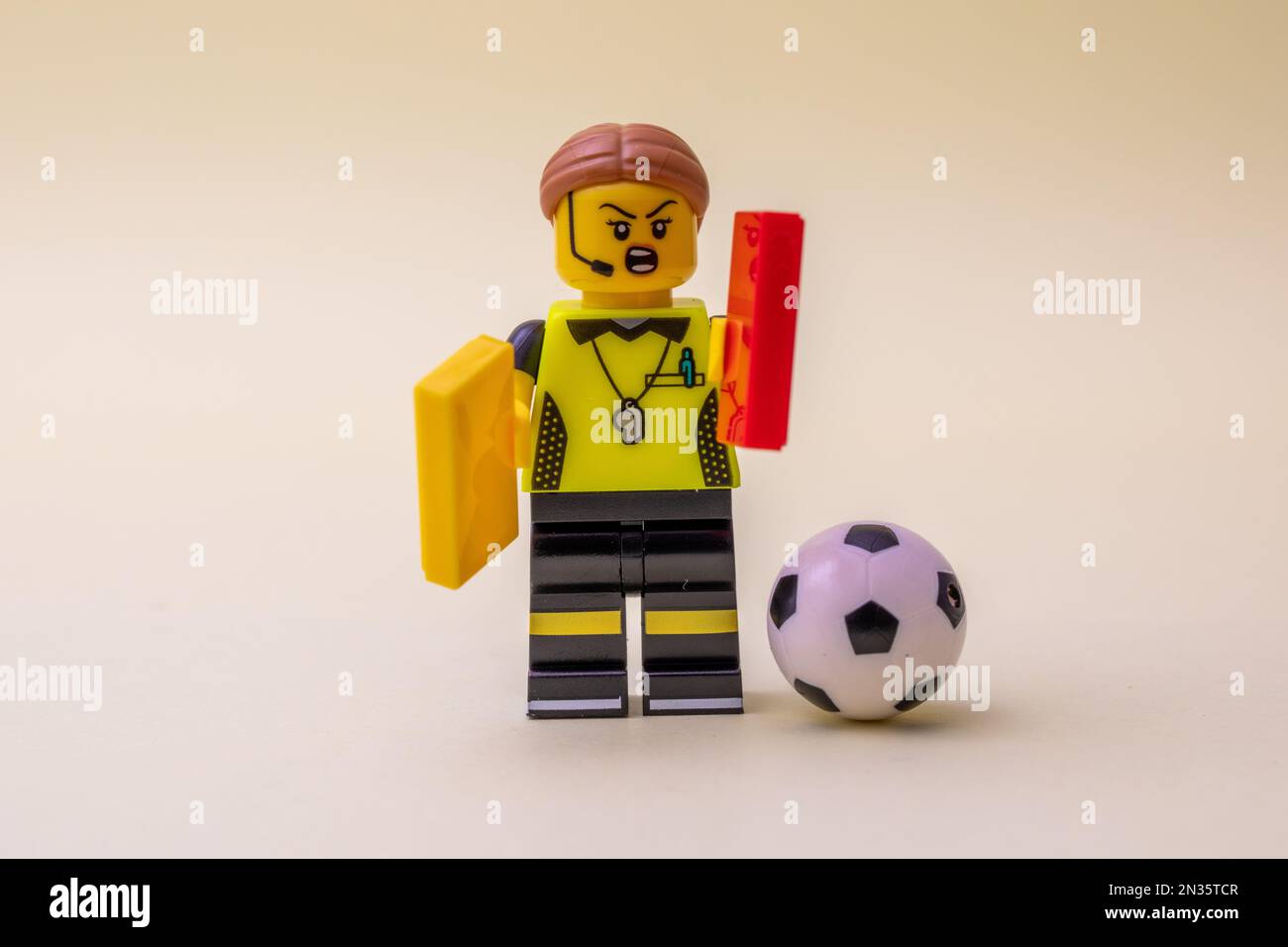 Un piccolo arbitro Lego figurina con carte e una palla isolato su uno sfondo chiaro Foto Stock