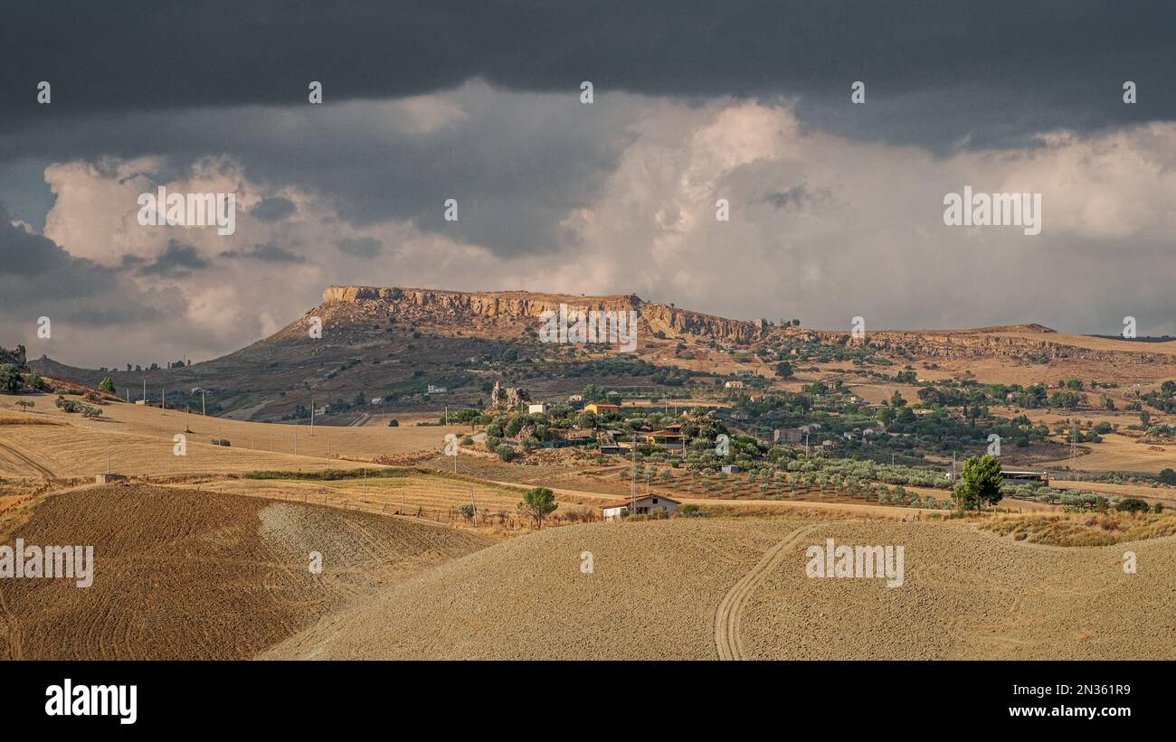Zona agricola nell'entroterra della Sicilia sud-occidentale in un pomeriggio nuvoloso e soleggiato; provincia di Agrigento, Italia Foto Stock