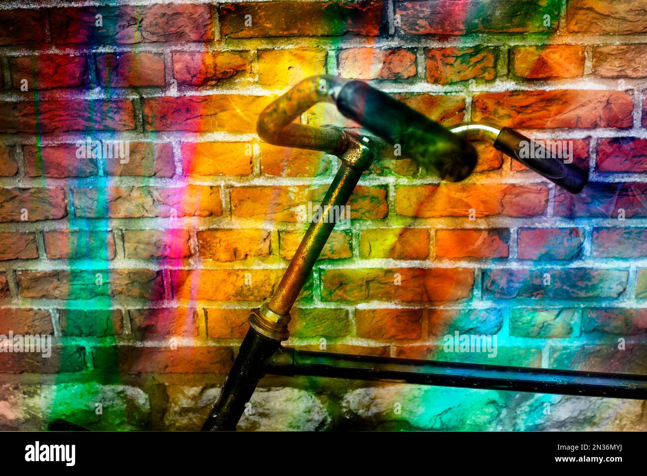 Vecchia bicicletta appoggiata contro una parete di mattoni e colori dell'arcobaleno Foto Stock