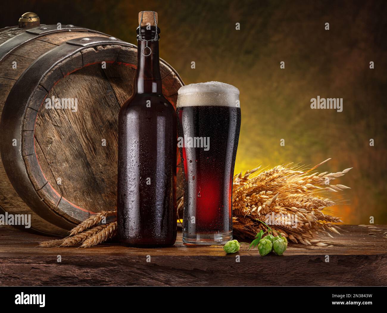 Bicchiere di birra nera artigianale, bottiglia di birra e botte di legno sul tavolo di legno della cantina. Foto Stock