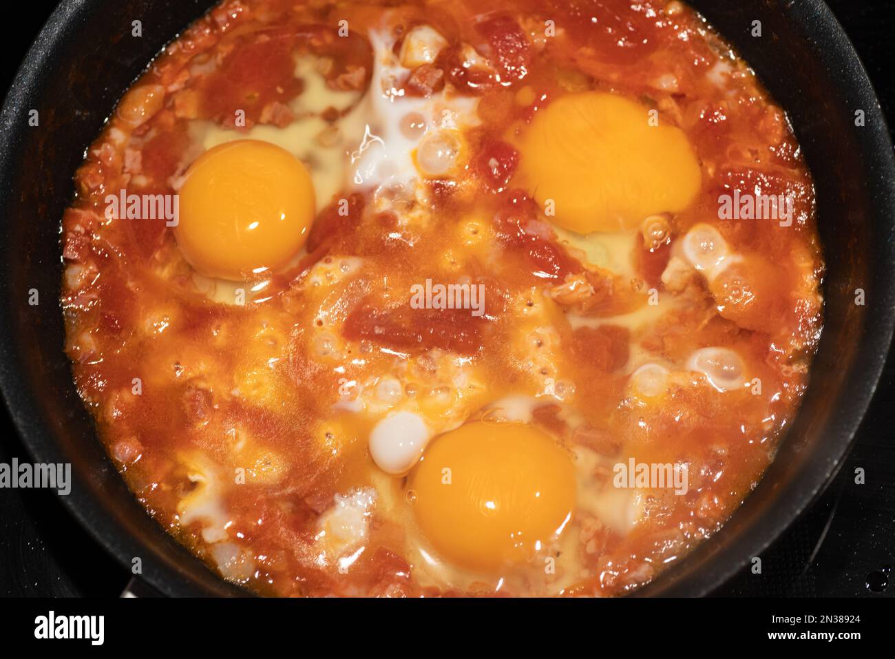 Cucina shakshouka in una padella di ferro vista dall'alto. Foto Stock