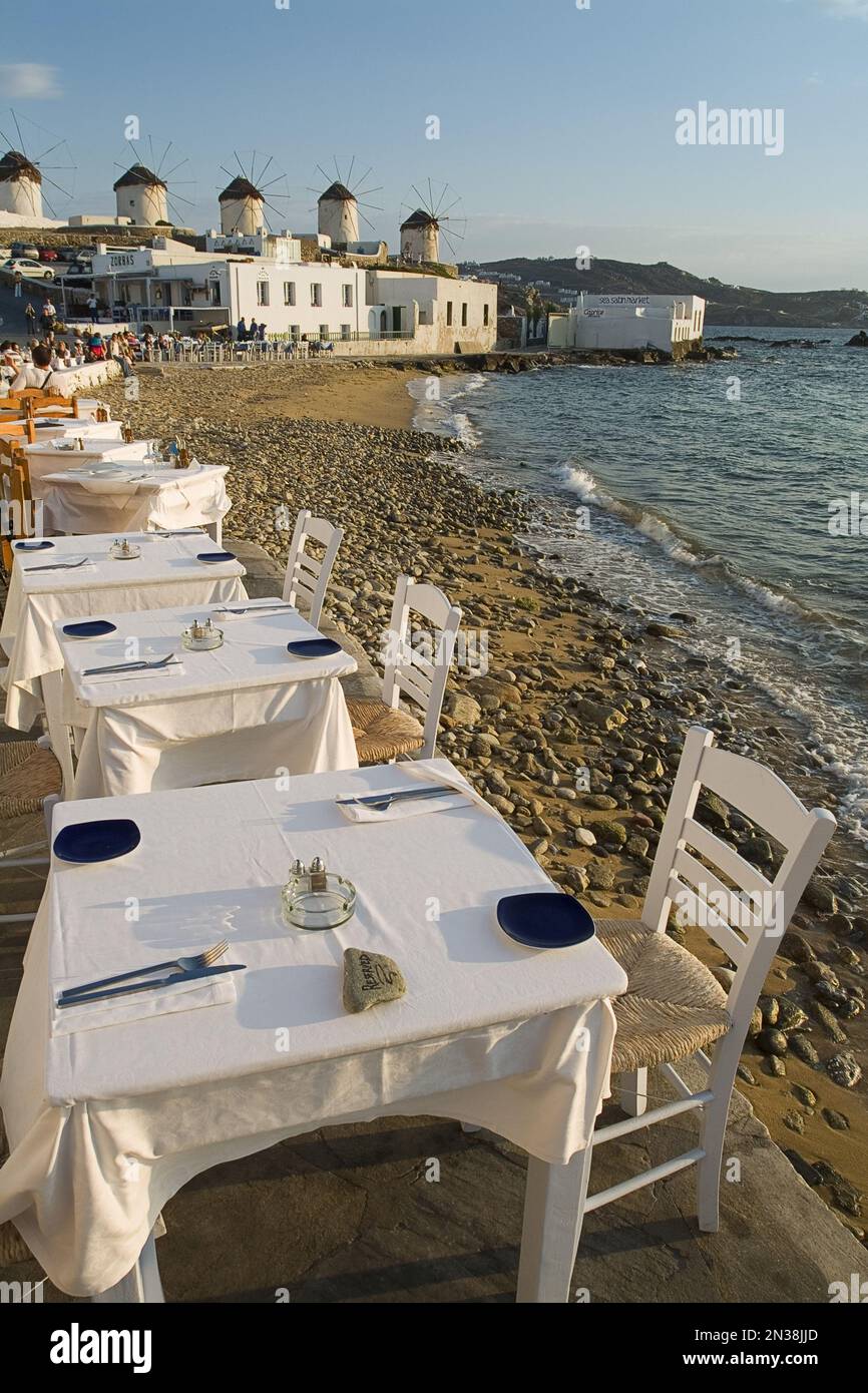 Ristorante Tavoli lungo la spiaggia e la città di Mykonos, Mykonos, Cicladi, Grecia Foto Stock