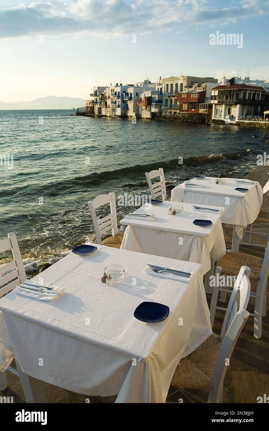 Ristorante Tavoli lungo la spiaggia e la città di Mykonos, Mykonos, Cicladi, Grecia Foto Stock