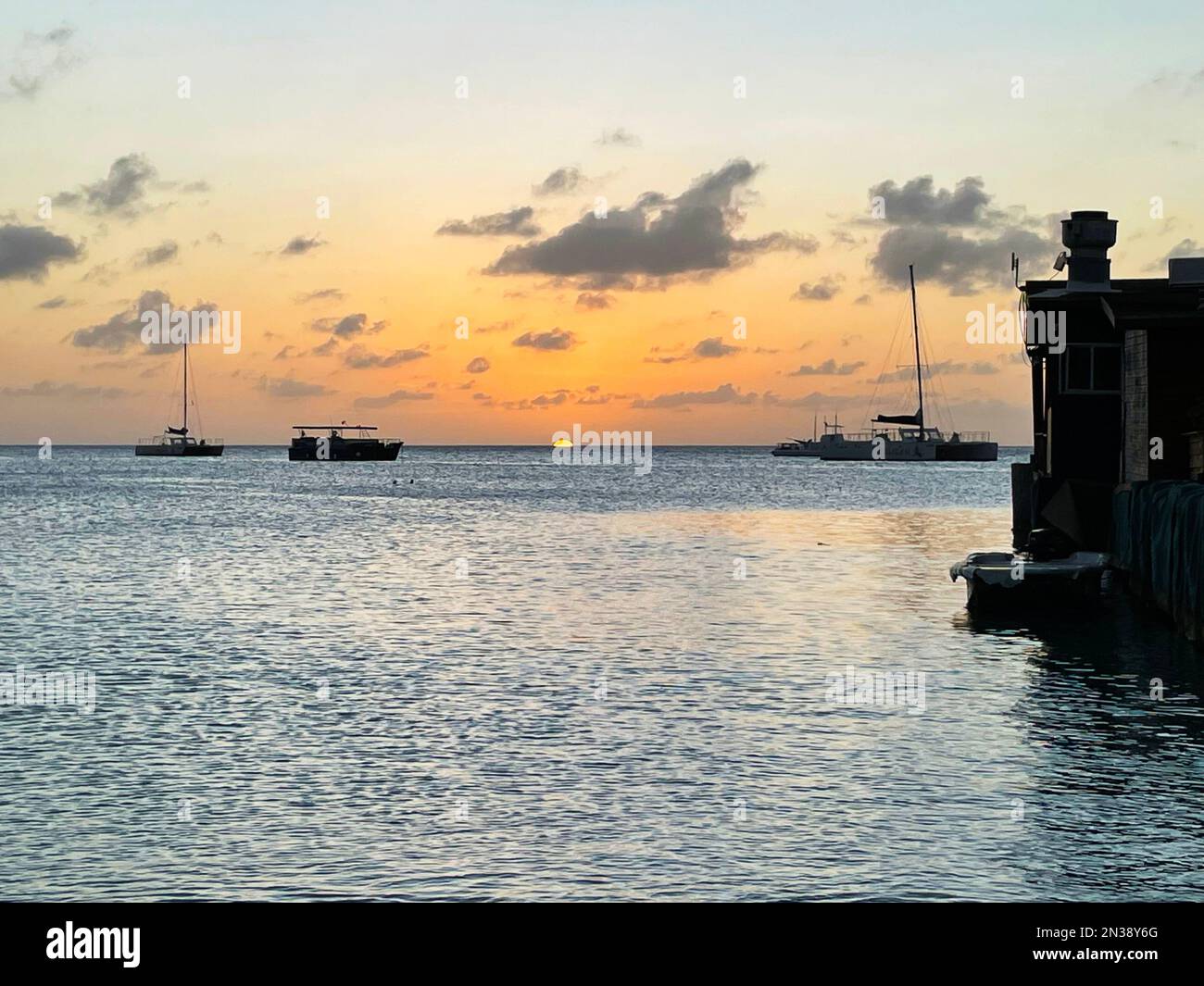 Barche a vela all'orizzonte al tramonto, sul mare dei Caraibi, al largo della costa di Aruba Foto Stock