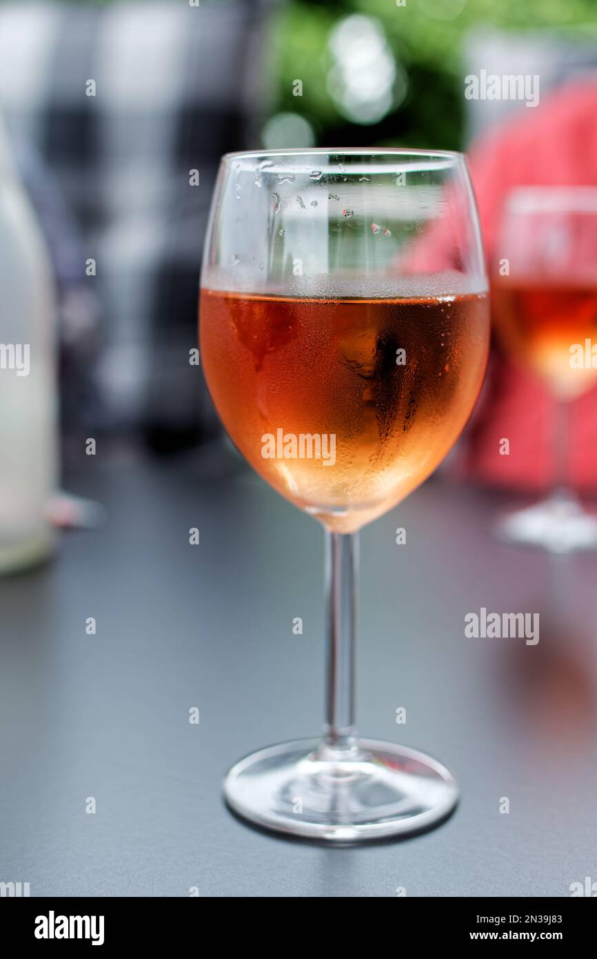 Bevanda di colore rosa in bicchiere di vino su sfondo sfocato Foto Stock