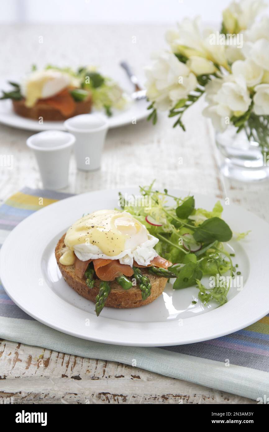 Asparagi e uova di salmone affumicate benedict con verdure a foglia su piatto bianco Foto Stock