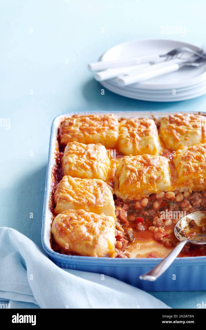Casseruola di fagioli con salsa di cheddar su sfondo blu Foto Stock