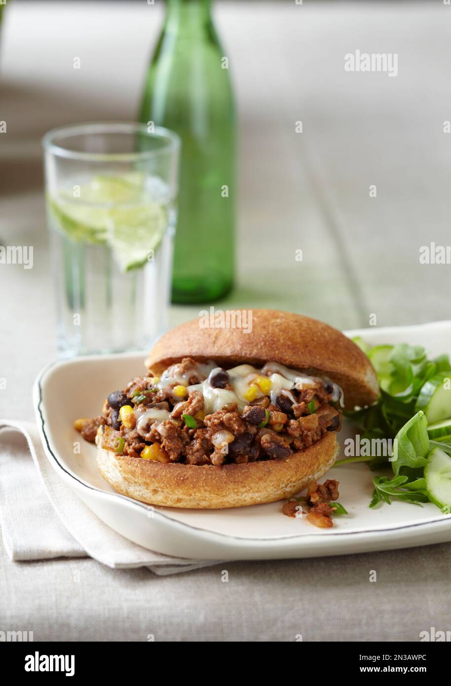 Joe sciatto su un panino integrale con contorno di insalata e un bicchiere d'acqua Foto Stock