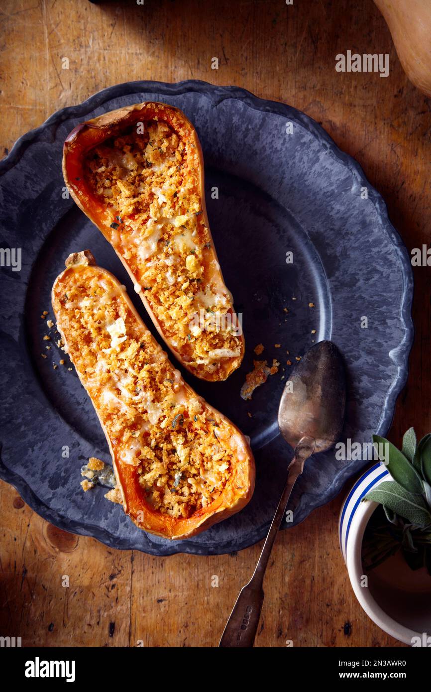 Zucca di zucca farcita al forno con formaggio e salvia su un piatto blu Foto Stock