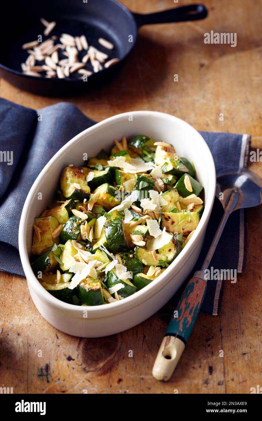 Zucchine arrostite con parmigiano rasato e mandorle tostate in un piatto ovale da portata Foto Stock