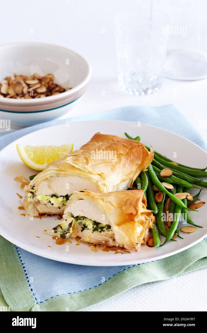 Pollo ripieno avvolto in pasta phyllo con fagioli verdi alle mandorle a lato Foto Stock