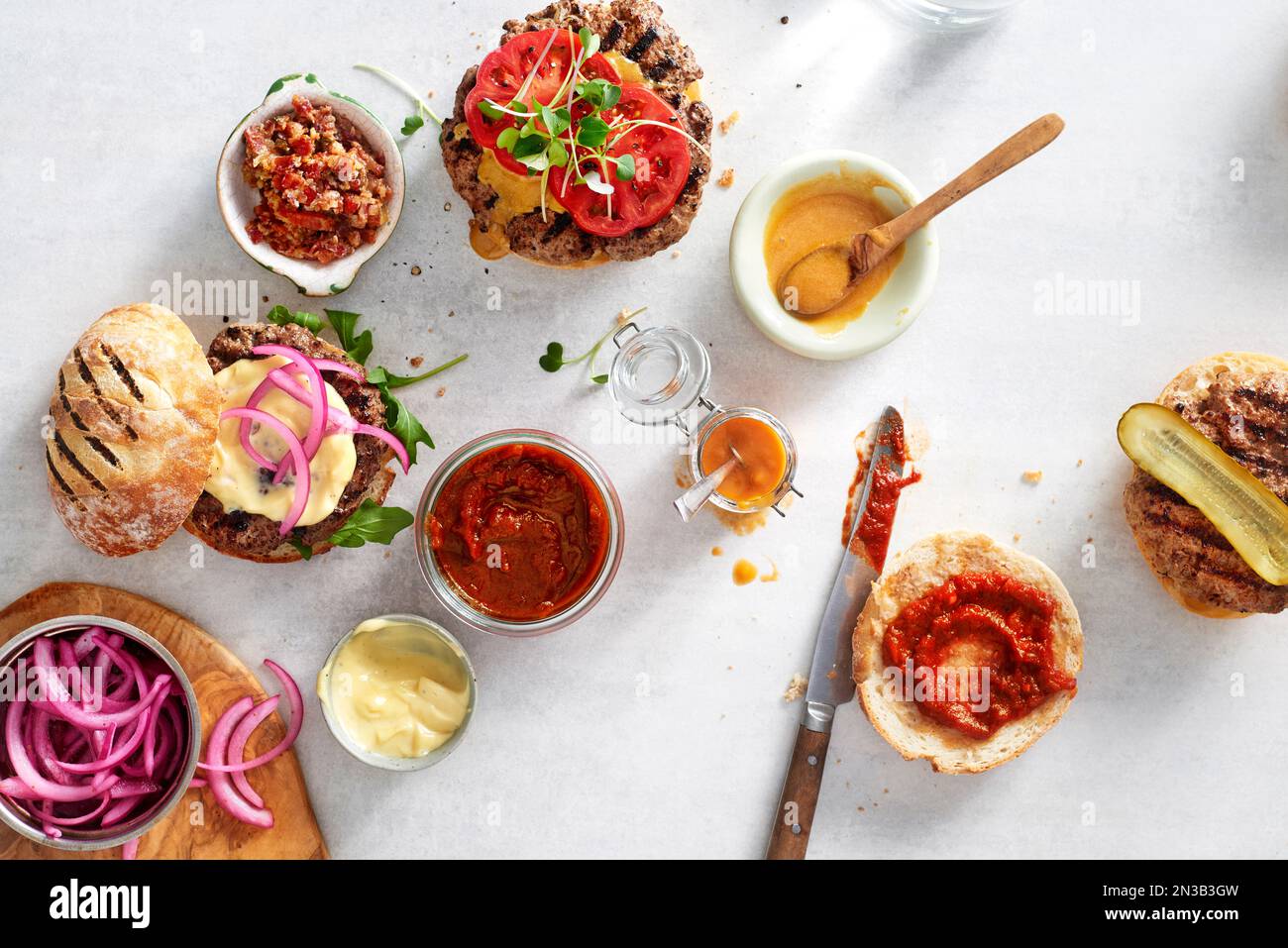 Hamburger con vari condimenti su una superficie di pietra leggera Foto Stock