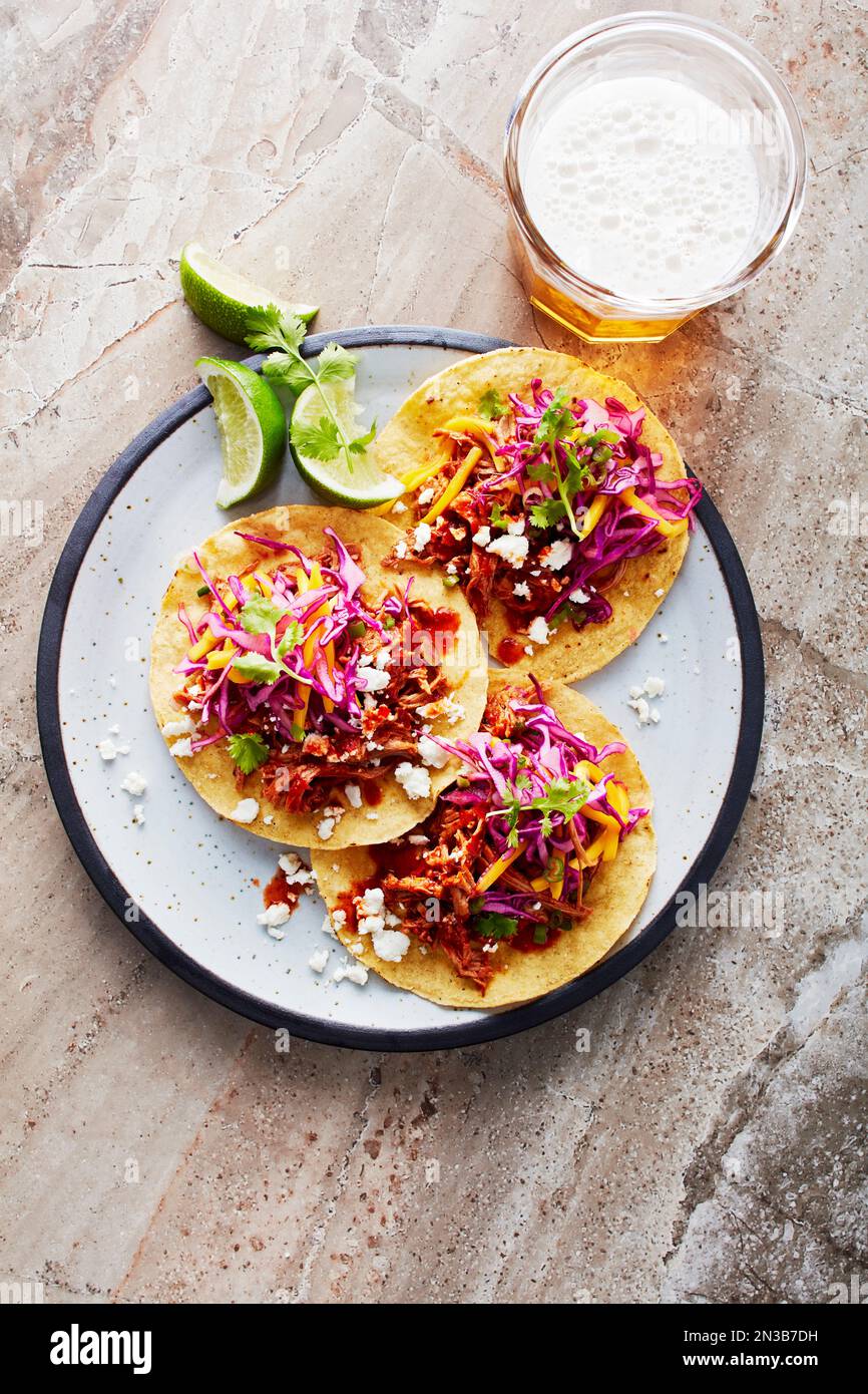 Tacos di pollo su un piatto con limes e un bicchiere di birra Foto Stock
