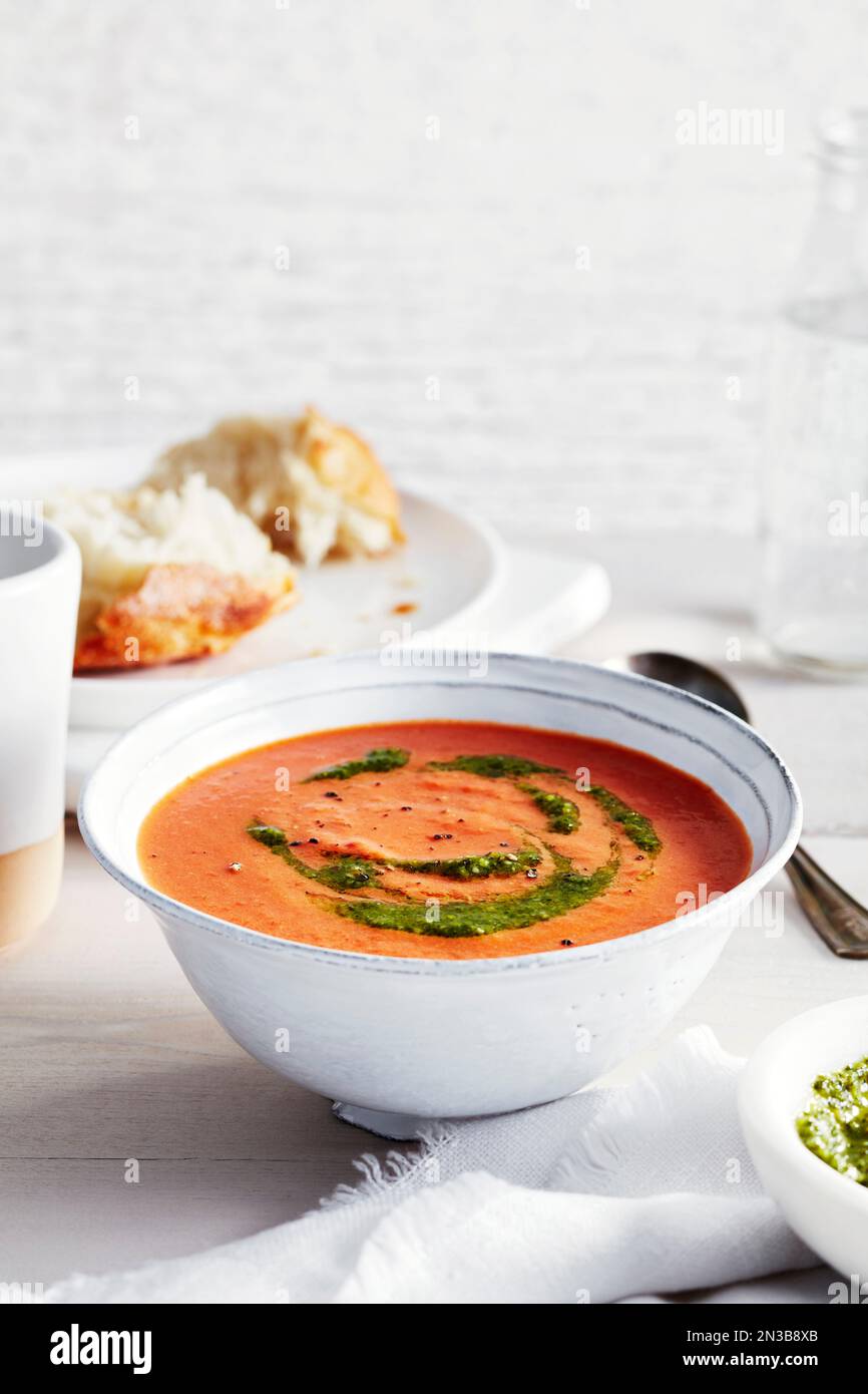 Zuppa di pomodoro con pesto e un contorno di pane croccante sullo sfondo Foto Stock