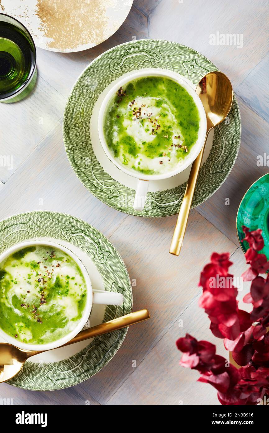 Zuppa di crescione in tazze da tè con cucchiai e fiori Foto Stock