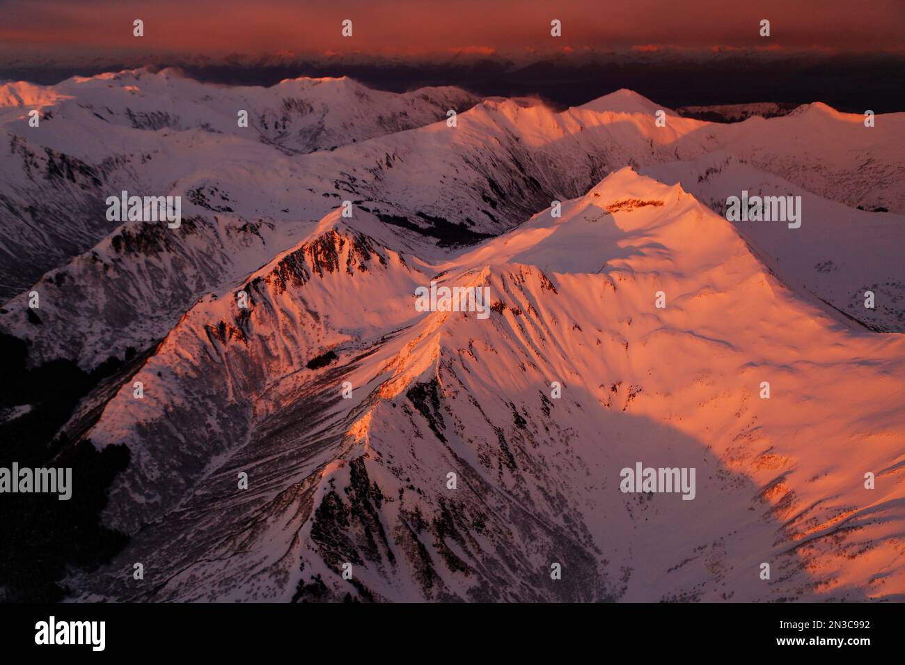 Le vette del monte South Chilkat sono baciate dalla luce calda al tramonto sopra lo stretto ghiacciato. I venti forti spazzano il ghiaccio e la neve dalle cime del crinale creando un... Foto Stock