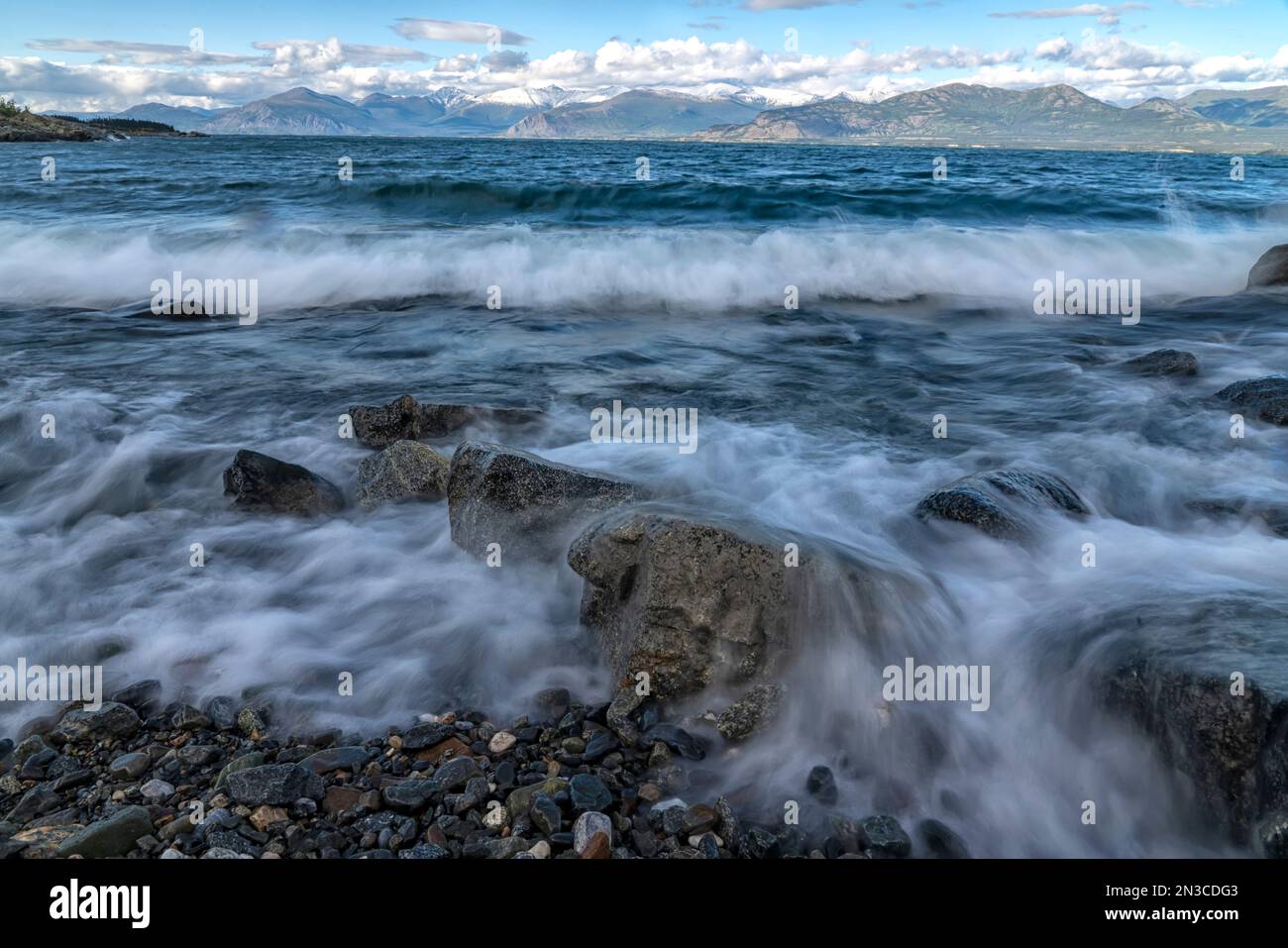 Le onde si infrangono sulla costa rocciosa del lago Kluane in una giornata ventosa. Il lago Klaune è il più grande lago dello Yukon; Yukon, Canada Foto Stock