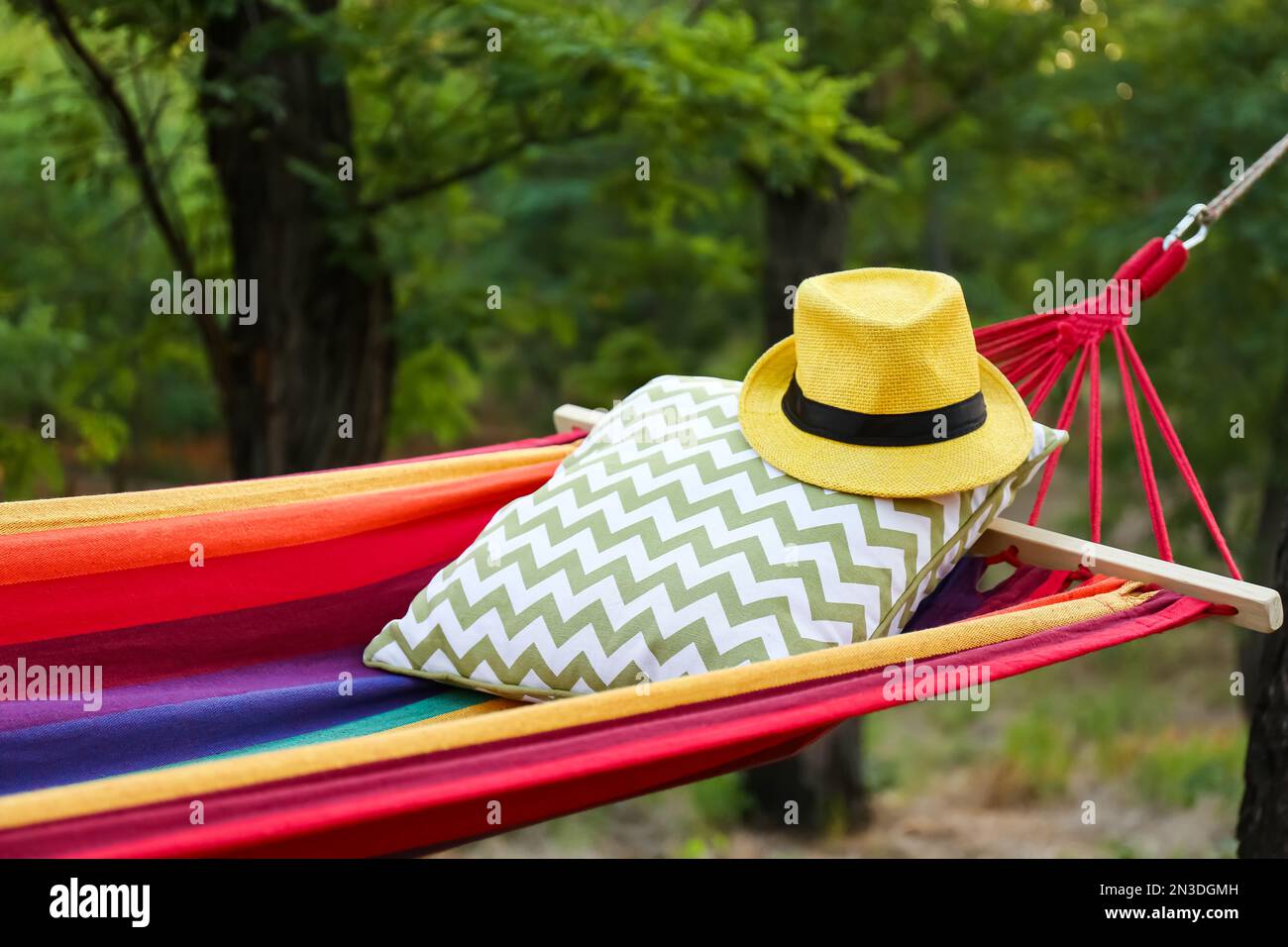 Amaca luminosa e confortevole con morbido cuscino e cappello al giardino verde, primo piano Foto Stock