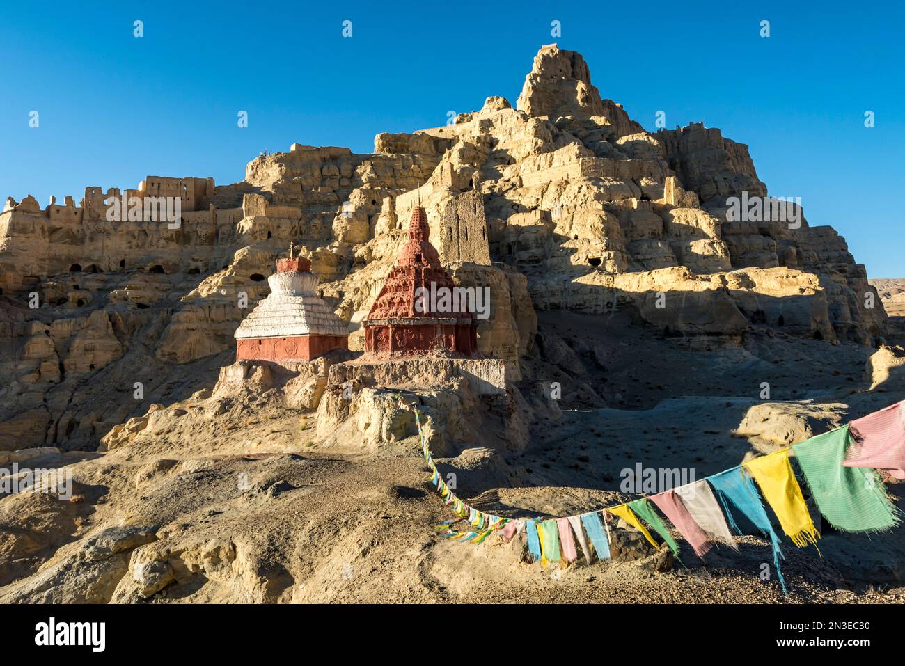 Rovine del regno di Guge con bandiere di preghiera nel paesaggio montano della valle di Sutlej nelle montagne dell'Himalaya Foto Stock