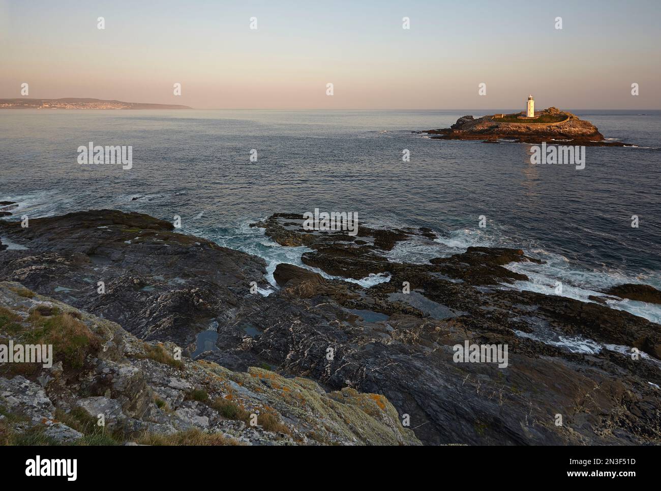 Faro di Godrevy sull'isola di Godrevy visto dalle scogliere rocciose all'estremità orientale della baia di St Ives, vicino a St Ives Foto Stock