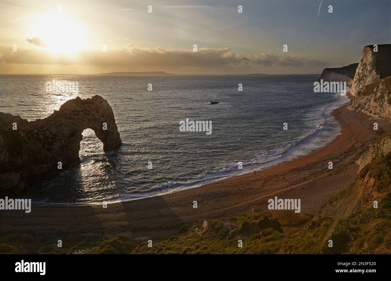 Una persona sola si trova sulla riva dell'Oceano Atlantico accanto alla formazione rocciosa Durdle Door sulla Jurassic Coast vicino a Lulworth Foto Stock