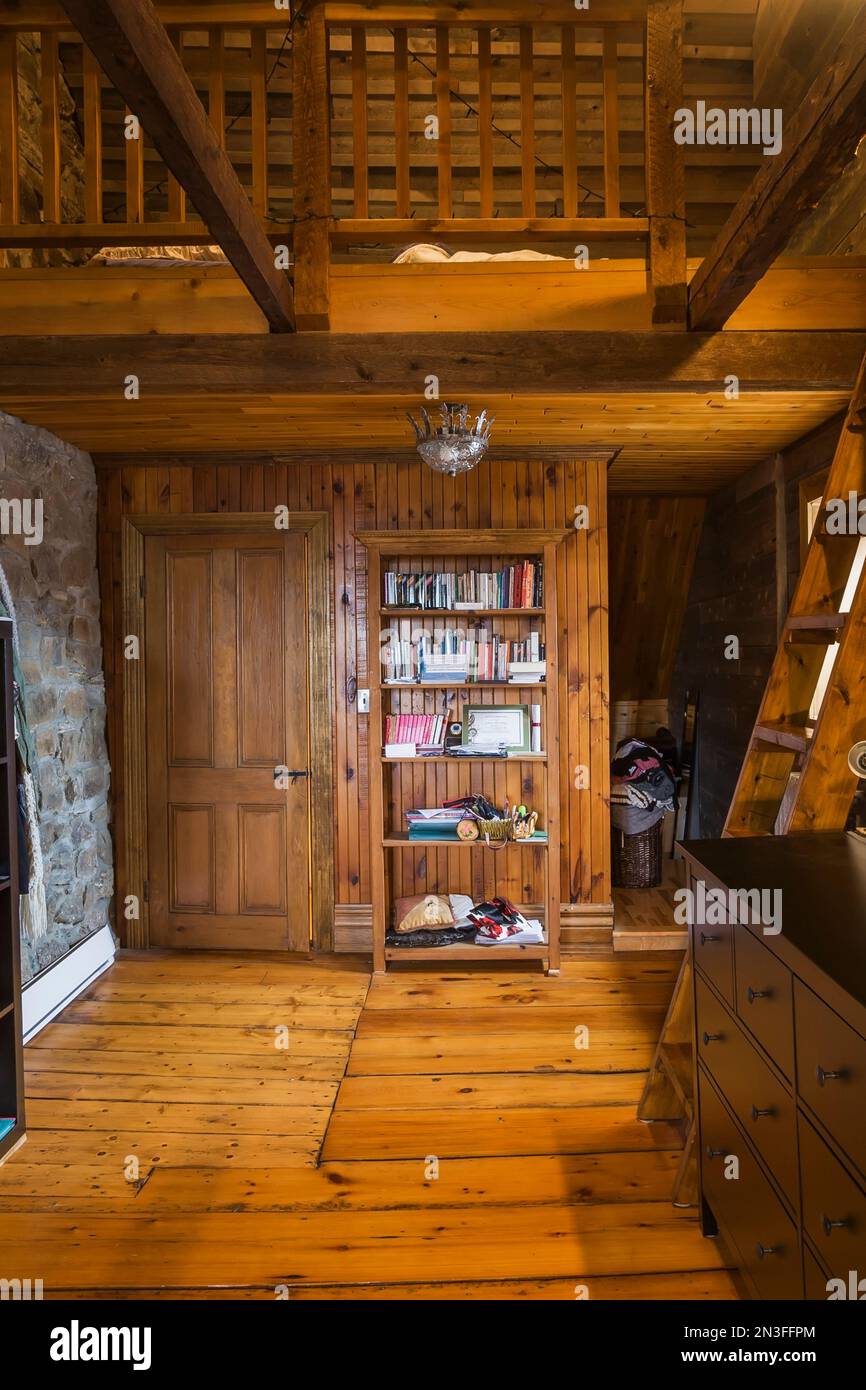 Camera da letto mansardata con ampi pavimenti in legno di pino, scale Miller e letto situato sul soppalco all'interno della vecchia casa in pietra di Canadiana del 1752 circa. Foto Stock
