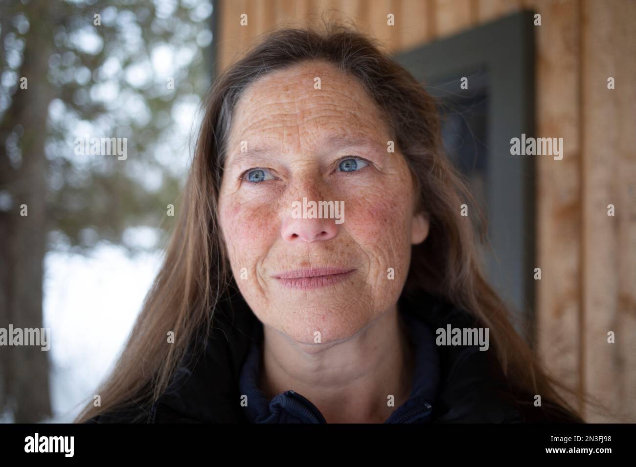 Ritratto di una donna matura in piedi all'aperto con una faccia lentigginata e occhi blu che guardano verso l'alto; Ottawa Valley, Ontario, Canada Foto Stock