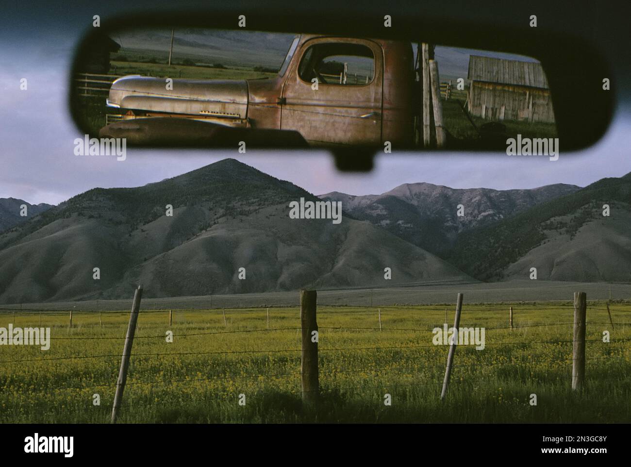 Vecchio camion e fienile riflessi nello specchietto retrovisore del veicolo; May, Idaho, Stati Uniti d'America Foto Stock