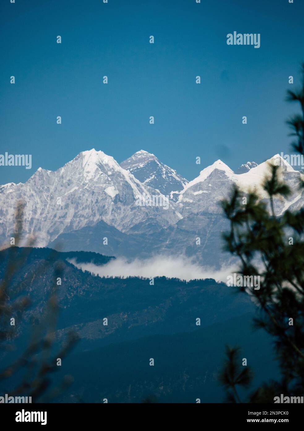 Uno scatto verticale delle cime dell'Himalaya ricoperte di neve con un cielo blu sullo sfondo, in Asia Foto Stock