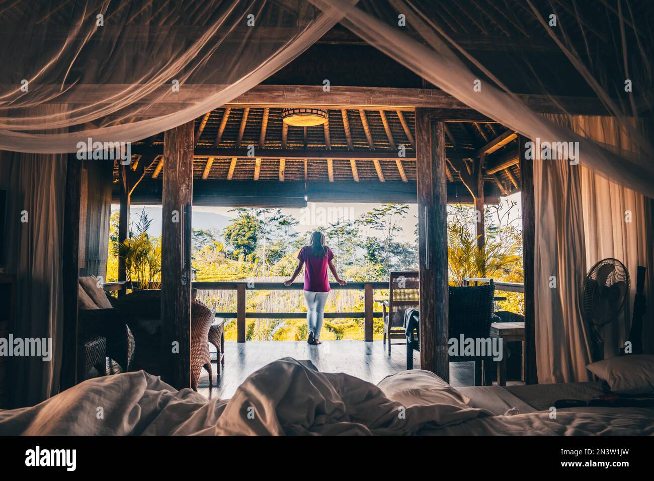 Vista da un letto a baldacchino nell'atmosfera mattutina, bungalow in legno nelle risaie di Sidemen, Bali, Indonesia Foto Stock