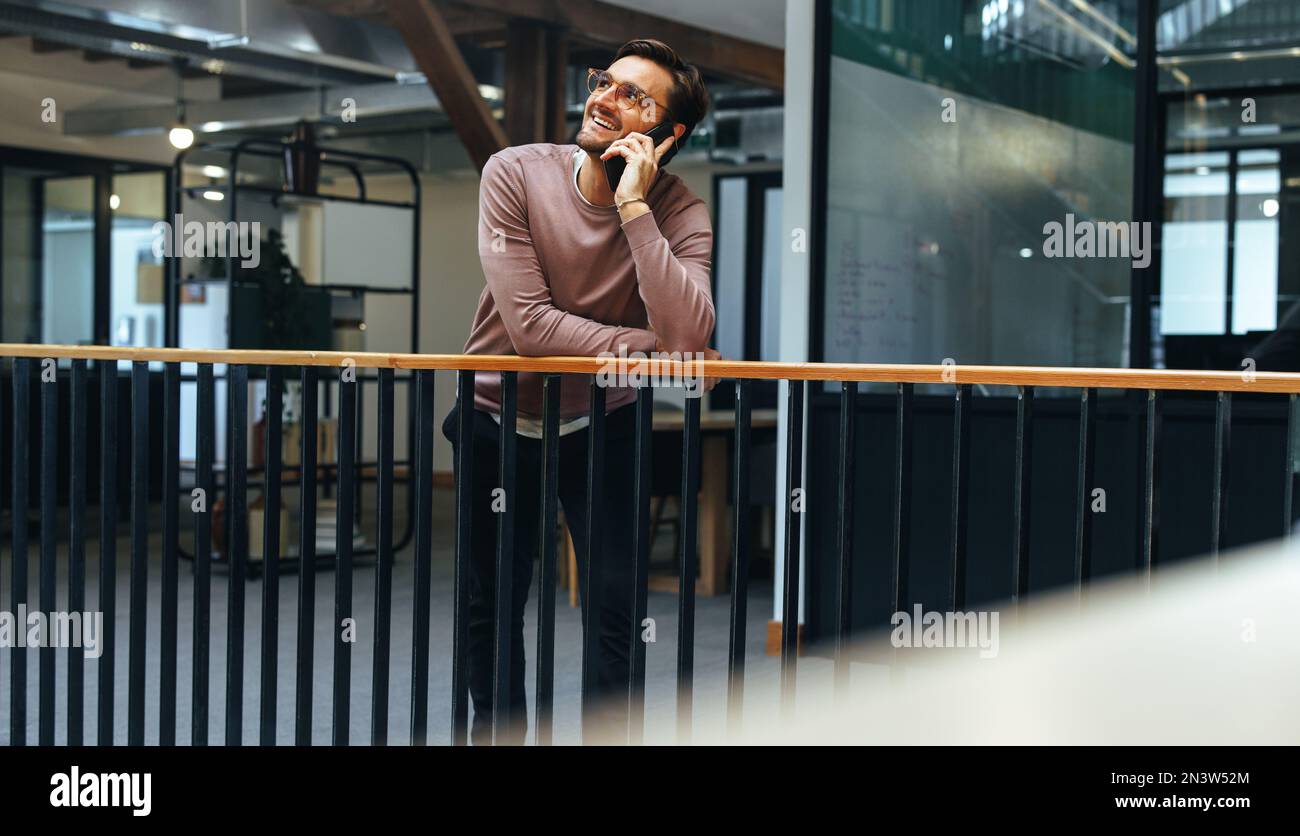 uomo d'affari che parla al telefono cellulare di un ufficio. Un professionista di sesso maschile che chiama i clienti su un cellulare. Comunicazione e networking in t Foto Stock