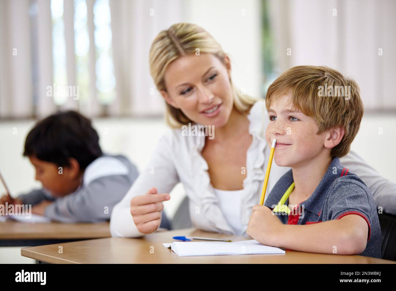 SA come far risconoscere il meglio ai suoi studenti. Un ragazzino che pensa ad un problema mentre il suo insegnante si siede accanto a lui. Foto Stock