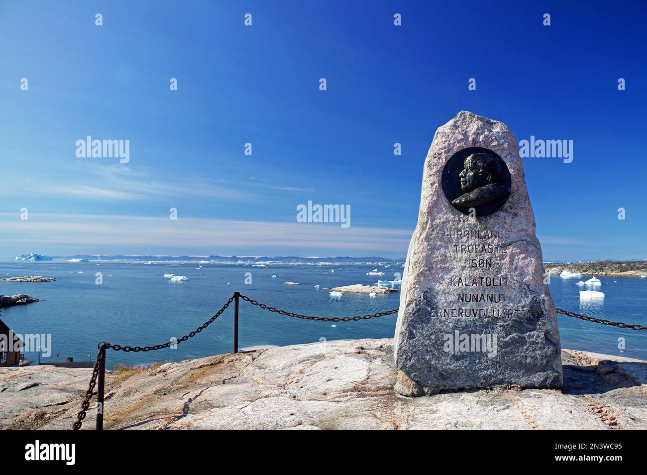 Monumento in pietra su una collina per l'esploratore e scopritore Knud Rasmussen, iceberg in un'ampia baia, Ilulisssat, Artico, Goernland, danimarca Foto Stock