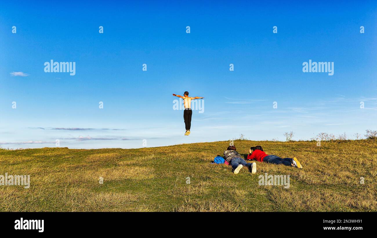 Giovani sul bordo di una scogliera, uomo che salta in aria, braccia tese, Beachy Head, Eastbourne, East Sussex, Inghilterra, Gran Bretagna Foto Stock