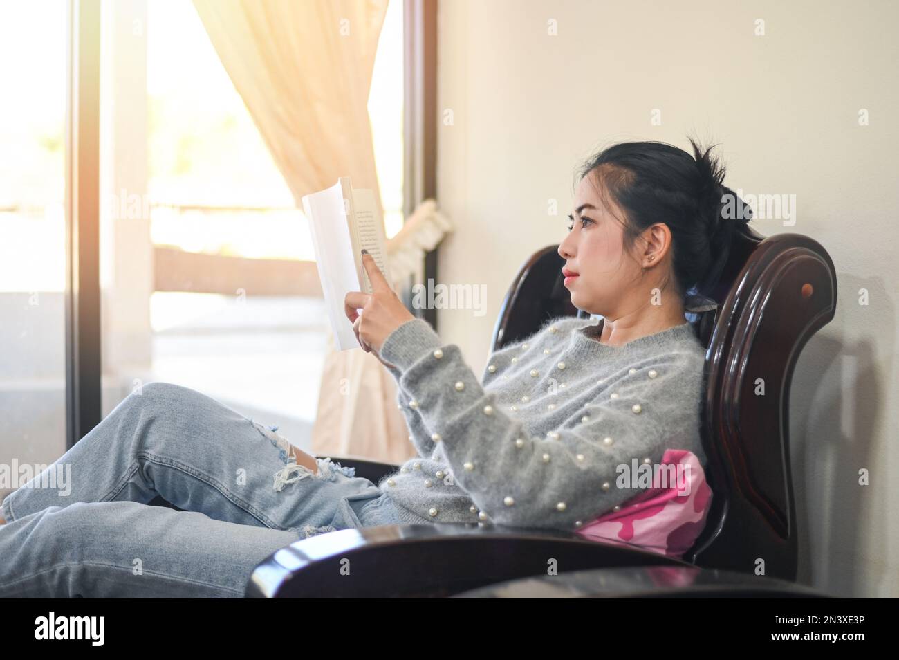 donna che si rilassa a casa, donna lettura libro deporre su divano di legno - rilassarsi nel suo soggiorno leggere libro in vacanza è preferito hobby in casa an Foto Stock