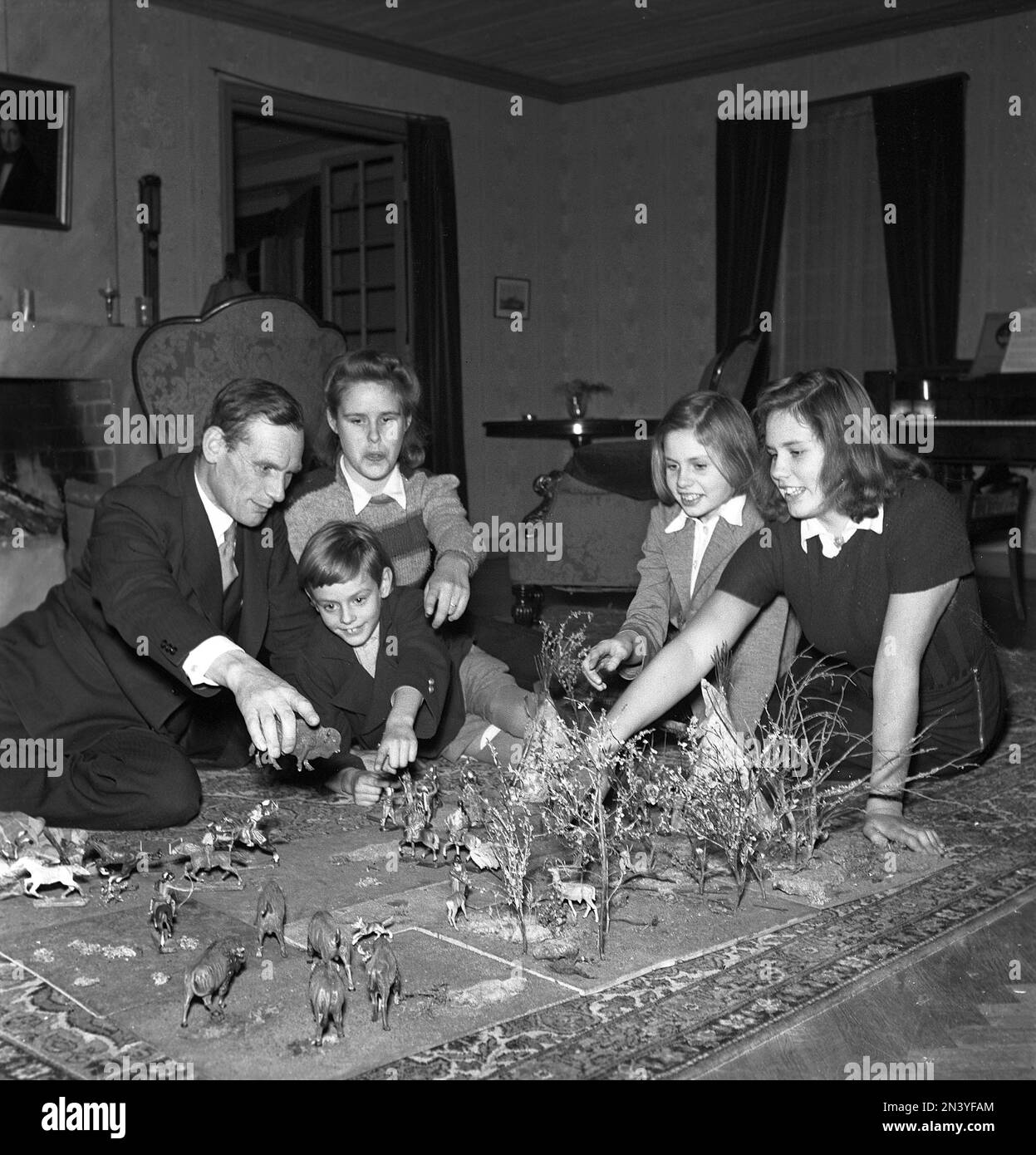 Giocattoli negli anni '1940s. Una famiglia è raccolta sul pavimento che gioca con le figure dei cowboy e della gente indigena americana, al tempo denominato indiani. I dati sono stati prodotti principalmente dalle società tedesche Elastolin e Lineol, la differenza essendo la base della strega su cui sono state montate le cifre. Elastolin aveva una base rettangolare. Svezia 1943 Kristoffersson Ref B20-1 Foto Stock